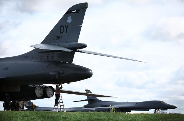 Members of the US Air Force (USAF) work on USAF B-1 Lancer bomber jets parked on the tarmac at RAF Fairford in south-west England on March 10, 2026. Fairford is one of two bases, along with the Diego Garcia facility in the Indian Ocean, that the UK has given the US permission to use for "specific defensive operations into Iran" to destroy Iranian missiles at source, the British defence minister said in a statement. (Photo by Henry Nicholls / AFP)