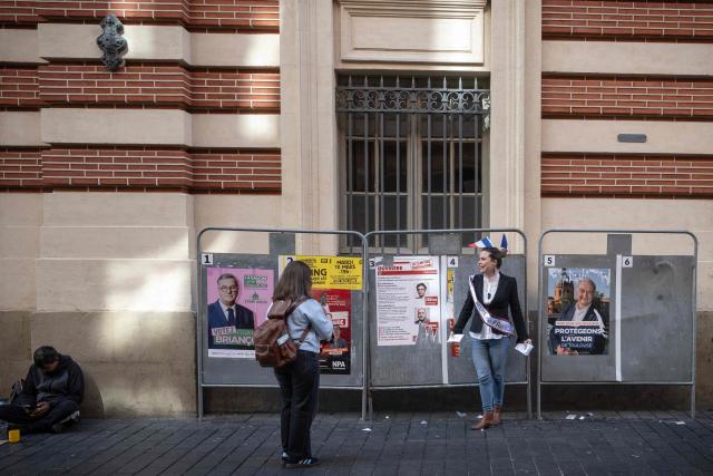 Women records a video in front of a panel displaying campaign posters of mayoral candidates for the upcoming municipal elections in Toulouse on March 10, 2026. (Photo by Lionel BONAVENTURE / AFP)