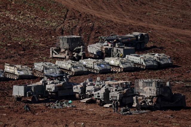 Israeli army soldiers gather near armoured military vehicles deployed at a position in the upper Galilee in northern Israel near the Lebanon border on March 10, 2026. A strike hit Beirut's southern suburbs on March 10, state media reported, after the Israeli military renewed its warning for people to evacuate the area. Israel's military began striking southern Lebanon on March 4 after issuing a call to evacuate all areas south of the country's Litani river. Lebanon was drawn into the Middle East war when Iran-backed militant group Hezbollah attacked Israel in response to the killing of Iranian supreme leader during US-Israeli strikes. (Photo by AHMAD GHARABLI / AFP)