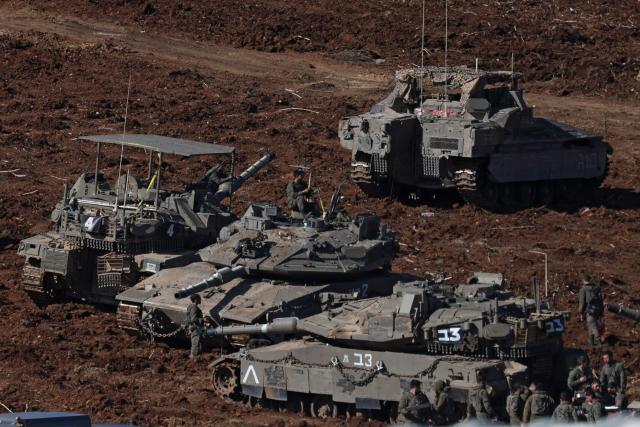 Israeli army soldiers gather near main battle tanks deployed at a position in the upper Galilee in northern Israel near the Lebanon border on March 10, 2026. A strike hit Beirut's southern suburbs on March 10, state media reported, after the Israeli military renewed its warning for people to evacuate the area. Israel's military began striking southern Lebanon on March 4 after issuing a call to evacuate all areas south of the country's Litani river. Lebanon was drawn into the Middle East war when Iran-backed militant group Hezbollah attacked Israel in response to the killing of Iranian supreme leader during US-Israeli strikes. (Photo by AHMAD GHARABLI / AFP) / Attention editors: AFP covers the war in the Middle East through its extensive regional network, including bureaus in Tehran, Jerusalem and several neighboring countries.Since the start of the conflict, journalists have been working under increasingly restrictive conditions. Authorities in several countries have limited reporters movements, photo and live video coverage from sensitive locations. Some governments and armed groups have banned images of missile or drone strikes and other security-related sites. / 