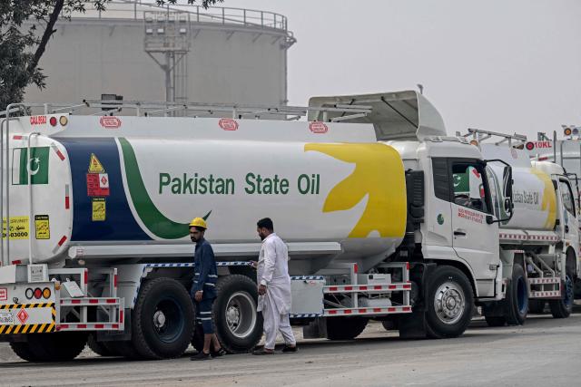 Workers inspect a Pakistan State Oil tanker as it lines up to enter a fuel storage facility in Sheikhupura district in Lahore on March 10, 2026. Pakistan's navy has launched an operation to "counter multidimensional threats" to its national shipping and maritime trade, with concerns about fuel supplies due to the US-Israeli war on Iran. (Photo by Arif ALI / AFP)