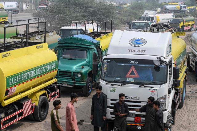 Pakistan State Oil tankers line up as workers inspect to enter a fuel storage facility in Sheikhupura district in Lahore on March 10, 2026. Pakistan's navy has launched an operation to "counter multidimensional threats" to its national shipping and maritime trade, with concerns about fuel supplies due to the US-Israeli war on Iran. (Photo by Arif ALI / AFP)