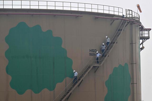 Workers descend through a staircase after inspection of the tank at the fuel storage facility in Sheikhupura district in Lahore on March 10, 2026. Pakistan's navy has launched an operation to "counter multidimensional threats" to its national shipping and maritime trade, with concerns about fuel supplies due to the US-Israeli war on Iran. (Photo by Arif ALI / AFP)