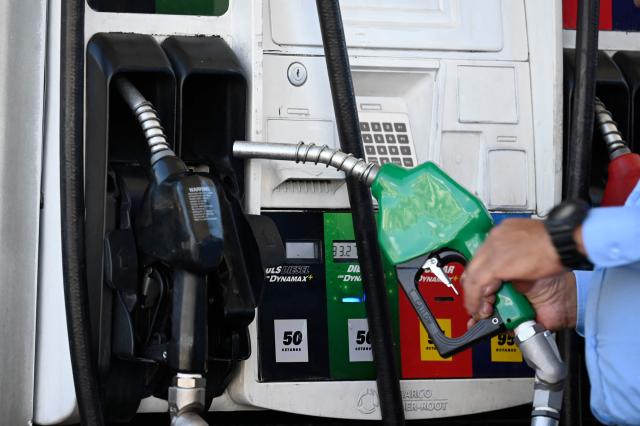 A man holds a fuel pump at a gas station in Guatemala City on March 10, 2026. The prices of petroleum derivatives soared in Guatemala due to the war in the Middle East. (Photo by JOHAN ORDONEZ / AFP)