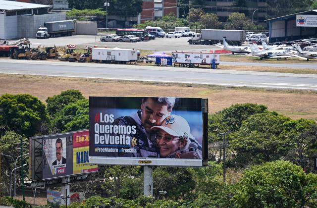Aerial view of a billboard depicting ousted Venezuela's President Nicolas Maduro and his wife, Cilia Flores, and reading "We want them back", is seen in Caracas on March 10, 2026. (Photo by Juan BARRETO / AFP)