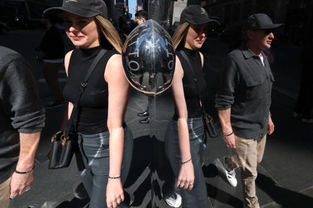 People are reflected on the side of a Louis Vuitton store on Fifth Avenue on March 10, 2026, as New York experiences springlike temperatures. (Photo by TIMOTHY A. CLARY / AFP)