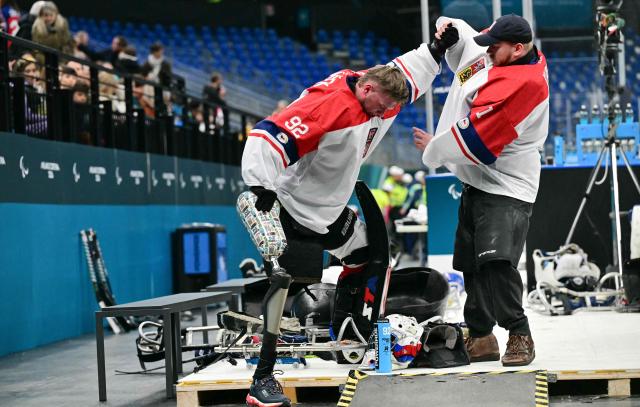 Czech Republic goalkeeper Patrik Sedlacek is helped by a teammate during the half time of the ice hockey match between Czech Republic and Canada at the Milano Cortina 2026 Paralympic Winter Games in Milan on March 10, 2026. (Photo by Stefano RELLANDINI / AFP)