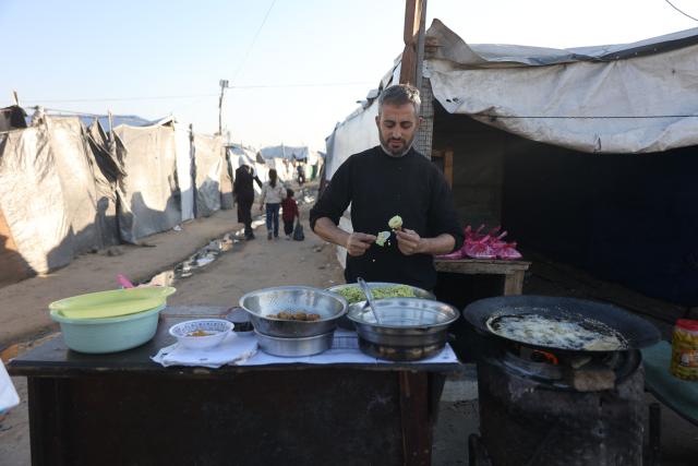A displaced Palestinian man prepares food next to a tent at the Jabalia refugee camp in the northern Gaza Strip on March 10, 2026. The majority of Gaza's 2.4 million people have been displaced, often multiple times, by the war that began with Hamas's attack on southern Israel on October 7, 2023. With displaced families living in tented camps, a serious concerns has been raised over their living conditions. (Photo by Omar AL-QATTAA / AFP)