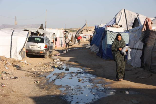 A displaced Palestinian woman walks in the street next to tents at the Jabalia refugee camp in the northern Gaza Strip on March 10, 2026. The majority of Gaza's 2.4 million people have been displaced, often multiple times, by the war that began with Hamas's attack on southern Israel on October 7, 2023. With displaced families living in tented camps, a serious concerns has been raised over their living conditions. (Photo by Omar AL-QATTAA / AFP)