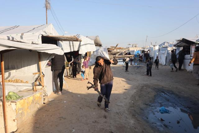 A displaced Palestinian man carries wood for fire at the Jabalia refugee camp in the northern Gaza Strip on March 10, 2026. The majority of Gaza's 2.4 million people have been displaced, often multiple times, by the war that began with Hamas's attack on southern Israel on October 7, 2023. With displaced families living in tented camps, a serious concerns has been raised over their living conditions. (Photo by Omar AL-QATTAA / AFP)