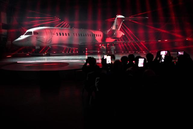 Guests take pictures with their smartphones during the unveiling ceremony of Dassault Aviation's new business aircraft the Falcon 10X at Dassault headquarters in Bordeaux, south-western France on March 10, 2026. Master of the Rafale fighter jets, French manufacturer Dassault has unveiled the Falcon 10X, its latest private jet. Rarer and more expensive than those of its North American competitors, it is eagerly awaited for its military-grade performance in a growing market. (Photo by Christophe ARCHAMBAULT / AFP)