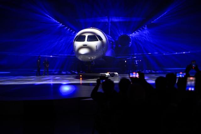 Guests take pictures with their smartphones during the unveiling ceremony of Dassault Aviation's new business aircraft the Falcon 10X at Dassault headquarters in Bordeaux, south-western France on March 10, 2026. Master of the Rafale fighter jets, French manufacturer Dassault has unveiled the Falcon 10X, its latest private jet. Rarer and more expensive than those of its North American competitors, it is eagerly awaited for its military-grade performance in a growing market. (Photo by Christophe ARCHAMBAULT / AFP)