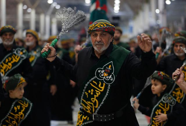 Shiite worshippers take part during a ritual commemorating the 7th century killing of Imam Ali, the cousin, son-in-law, and companion of the Prophet Muhammad, during the Muslim month of Ramadan in Iraq's holy city of Najaf on March 10, 2026. (Photo by AHMAD AL-RUBAYE / AFP)