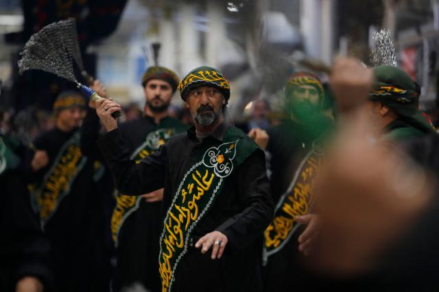 TOPSHOT - Shiite worshippers take part during a ritual commemorating the 7th century killing of Imam Ali, the cousin, son-in-law, and companion of the Prophet Muhammad, during the Muslim month of Ramadan in Iraq's holy city of Najaf on March 10, 2026. (Photo by AHMAD AL-RUBAYE / AFP)