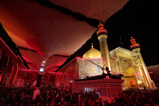 Shiite worshippers place copies of the Koran, Islam's holy book, on their heads during a ritual commemorating the 7th century killing of Imam Ali, the cousin, son-in-law, and companion of the Prophet Muhammad, during the Muslim month of Ramadan in Iraq's holy city of Najaf on March 10, 2026. (Photo by AHMAD AL-RUBAYE / AFP)