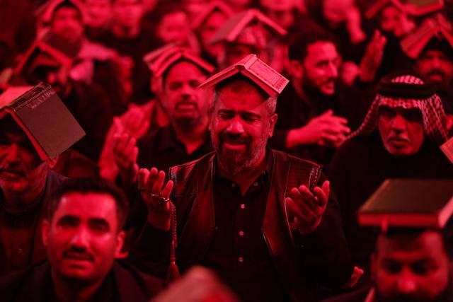 Shiite worshippers place copies of the Koran, Islam's holy book, on their heads during a ritual commemorating the 7th century killing of Imam Ali, the cousin, son-in-law, and companion of the Prophet Muhammad, during the Muslim month of Ramadan in Iraq's holy city of Najaf on March 10, 2026. (Photo by AHMAD AL-RUBAYE / AFP)