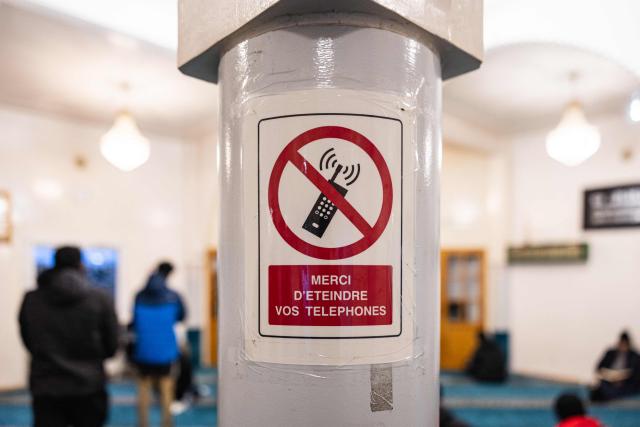 This photograph shows a sign prohibiting the mobile phone usage at the mosque as muslim faithfuls gather to break their fast with an Iftar meal during the fasting holy month of Ramadan in Calais, northern France on March 10, 2026. (Photo by Sameer Al-DOUMY / AFP)