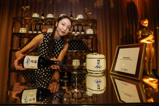Dassai brand ambassador Mayuko Boutroy pours a glass of Dassai blue sake at the 98th Oscars Governors Ball preview at the Ray Dolby Ballroom in Hollywood, California, on March 10, 2026. Austrian Chef Wolfgang Puck unveiled his menu for the Academy's official post Oscars celebration. (Photo by VALERIE MACON / AFP)