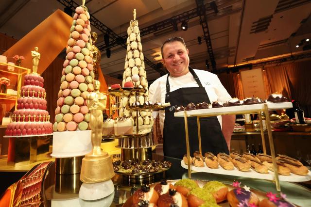 A chef poses next to a chocolate 'piece montee' at the 98th Oscars Governors Ball preview at the Ray Dolby Ballroom in Hollywood, California, on March 10, 2026. Austrian Chef Wolfgang Puck unveiled his menu for the Academy's official post Oscars celebration. (Photo by VALERIE MACON / AFP)