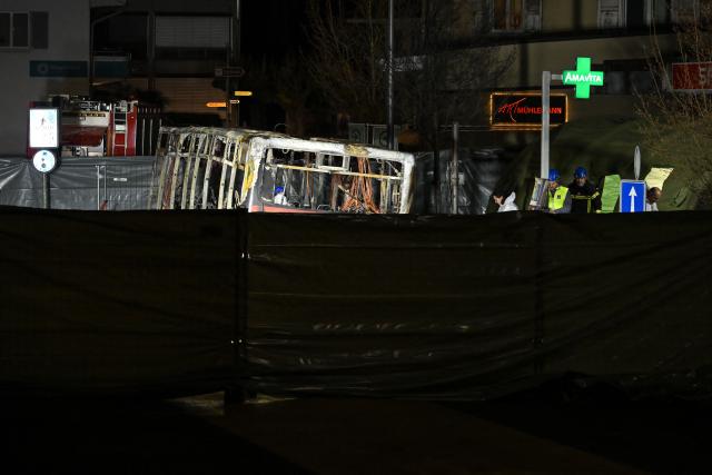 Forensic officers work in a screened-off area inside a bus that caught fire, killing at least six people and injuring five others in what police said may have been a deliberate act, in the town of Kerzers, western Switzerland, on March 11, 2026. A bus caught fire in western Switzerland on March 10 killing at least six people and injuring five others in what police said may have been a deliberate act. The fire broke out on the bus in the main street of the small town of Kerzers, around 20 kilometres (12 miles) west of the Swiss capital Bern, at about 6:25 pm (1725 GMT). (Photo by Fabrice COFFRINI / AFP)