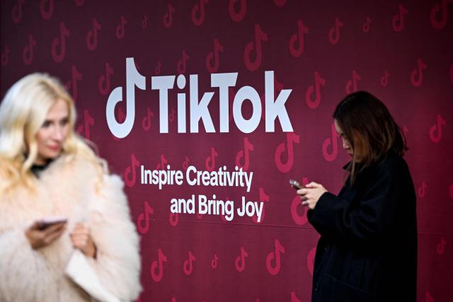 (FILES) Women use their phones in front of Tiktok's booth during the World Economic Forum (WEF) annual meeting in Davos on January 19, 2026. The Brazilian government sent an official letter to TikTok on March 10, 2026, demanding an explanation of the measures it takes to detect and remove misogynistic content, after videos simulating attacks on women went viral on the platform. (Photo by INA FASSBENDER / AFP)