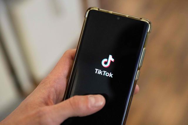 (FILES) This photograph taken on April 19, 2024 shows a man holding a smartphone displaying the logo of Chinese social media platform Tiktok in an office in Paris. The Brazilian government sent an official letter to TikTok on March 10, 2026, demanding an explanation of the measures it takes to detect and remove misogynistic content, after videos simulating attacks on women went viral on the platform. (Photo by Antonin UTZ / AFP)