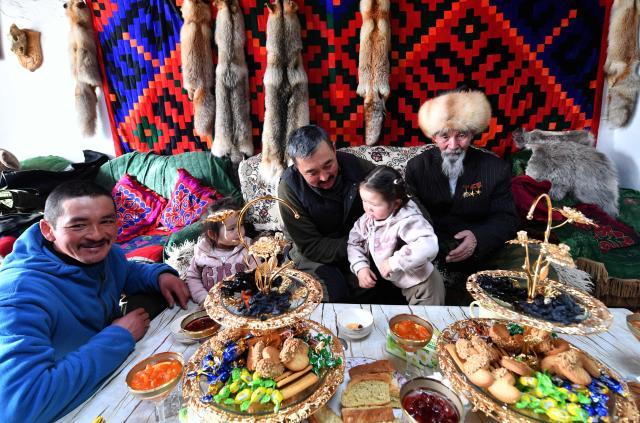 Amantur, 30, Baatyrbek, 52, and Tashtanbek, 88, of the Akmatov family of white yaks breeders, sit by a table in their house in the mountainous Kyrgyz village of Kara-Saz on February 3, 2026. (Photo by Vyacheslav OSELEDKO / AFP)