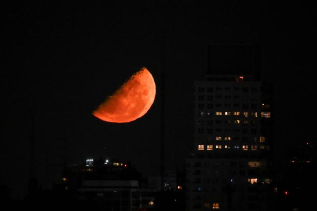 The half moon is seen over Buenos Aires on March 10, 2026. (Photo by Luis ROBAYO / AFP)