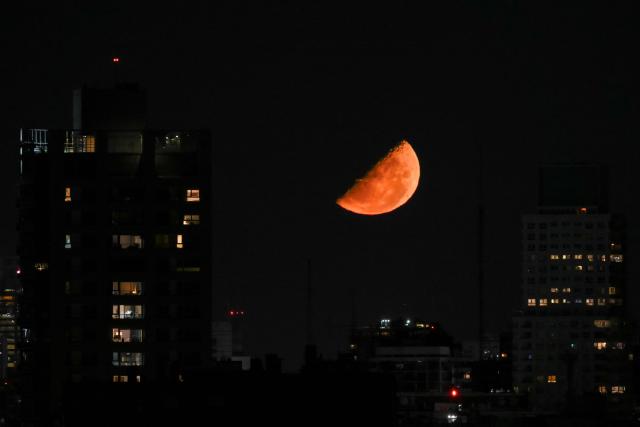 The half moon is seen over Buenos Aires on March 10, 2026. (Photo by Luis ROBAYO / AFP)