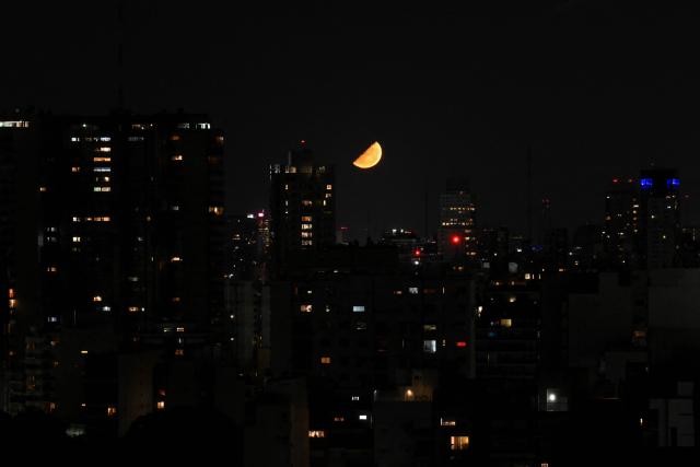 The half moon is seen over Buenos Aires on March 10, 2026. (Photo by Luis ROBAYO / AFP)