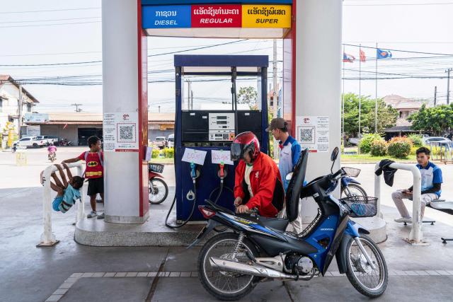 A motorist arrives to refuel his motorcycle at a gas station in the Donkoi district of Vientiane on March 10, 2026, amid rising petrol prices. The spike in oil prices caused by the war in the Middle East has provoked anxiety in many drivers across Asia. (Photo by AFP)