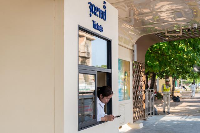 An employee checks her phone at a ticket booth of the Bus Rapid Transit (BRT) Patuxay station in Vientiane on March 10, 2026, as the public transportation system resumes in the Lao capital. (Photo by AFP)