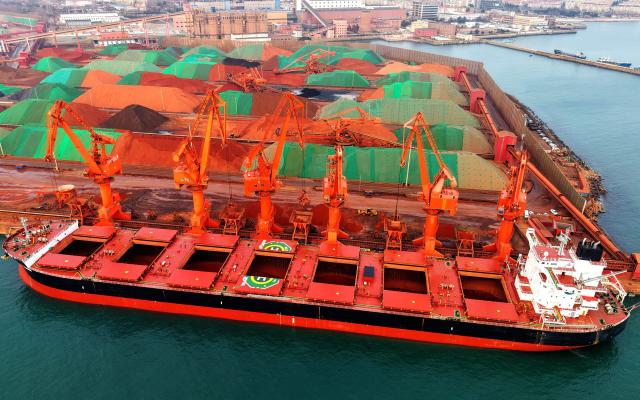 A cargo ship unloads iron ore at a port in Qingdao, in China’s eastern Shandong province on March 11, 2026. (Photo by CN-STR / AFP) / China OUT