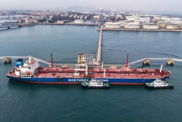 An oil tanker unloads crude oil at a terminal at the port in Qingdao, in China’s eastern Shandong province on March 11, 2026. (Photo by CN-STR / AFP) / China OUT
