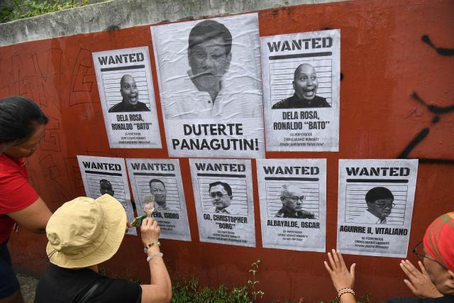 Relatives of drug suspects, who were allegedly illegally killed under orders from former Philippine president Rodrigo Duterte, post portraits of Duterte and his alleged co-perpetrators during a rally along a street in Manila on March 11, 2026, on the first anniversary of the former president's arrest and handover to the Netherland-based International Criminal Court (ICC). (Photo by Ted ALJIBE / AFP)