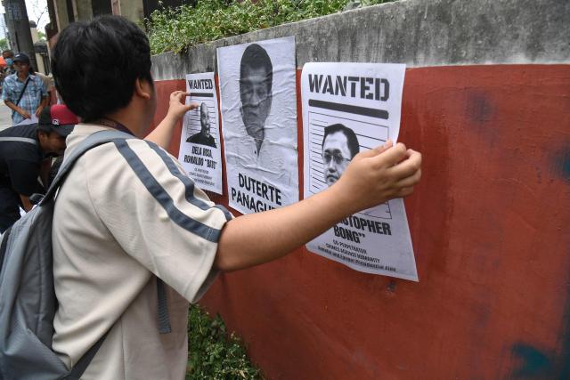Relatives of drug suspects, who were allegedly illegally killed under orders from former Philippine president Rodrigo Duterte, post portraits of Duterte and his alleged co-perpetrators during a rally along a street in Manila on March 11, 2026, on the first anniversary of the former president's arrest and handover to the Netherland-based International Criminal Court (ICC). (Photo by Ted ALJIBE / AFP)