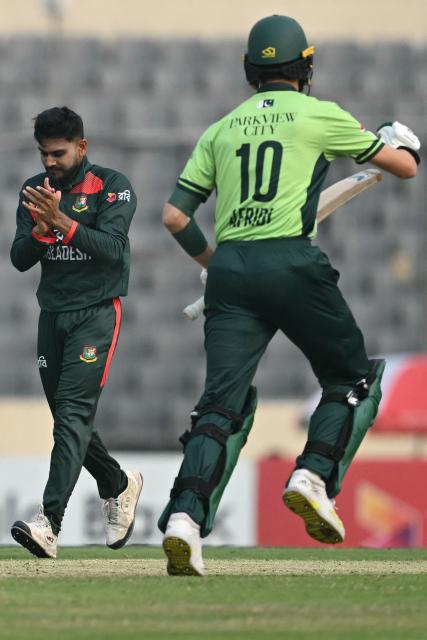 Bangladesh's Mehidy Hasan Miraz (L) celebrates after taking the wicket of Pakistan's Shaheen Shah Afridi (R) during the first one-day international (ODI) cricket match between Bangladesh and Pakistan at Sher-e-Bangla National Stadium in Mirpur on March 11, 2026. (Photo by MUNIR UZ ZAMAN / AFP)