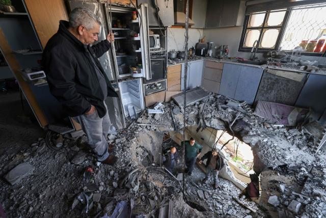Palestinians inspect damage which according to them was caused by fragments of an intercepted Iranian rocket that landed on a Palestinian three-story building in the West Bank town of Bidya, west of Salfit, on March 11, 2026. Israel's military said on March 11 it had begun a new "wide-scale wave of strikes" across Iran and was also hitting Hezbollah infrastructure in Lebanon's capital Beirut. The fresh strikes targeting what the Israeli army called "Iranian terror regime infrastructure" came on the 12th day of the US-Israeli war with Tehran. (Photo by JAAFAR ASHTIYEH / AFP)