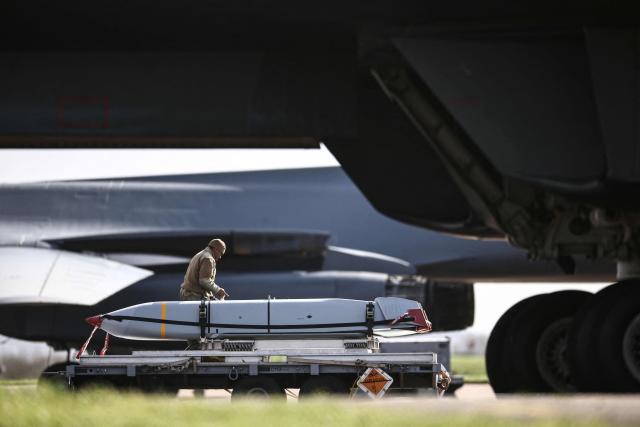 Military ground personnel are pictured next to cruise missiles which were unloaded from a US Air Force B-1 Lancer bomber on the tarmac at RAF Fairford in south-west England on March 11, 2026. Fairford is one of two bases, along with the Diego Garcia facility in the Indian Ocean, that the UK has given the US permission to use for "specific defensive operations into Iran" to destroy Iranian missiles at source, the British defence minister said in a statement. (Photo by Henry NICHOLLS / AFP)