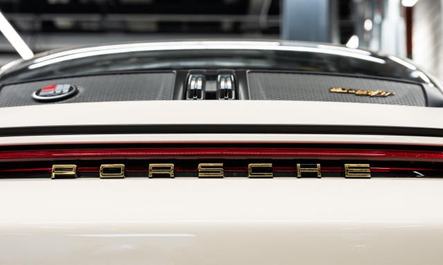 (FILES) The Porsche lettering is pictured on a Porsche 911 S/T at the "Exclusive Manufaktur" of German luxury car maker Porsche, where clients can get their vehicles customized in Stuttgart - Zuffenhausen on March 6, 2025. Porsche reiterated at a press conference on March 11, 2026 a desire to “extend the lifespan of its combustion and hybrid engines,” in the face of a slower-than-expected adoption of electric vehicles in Europe and the United States. (Photo by SILAS STEIN / AFP)