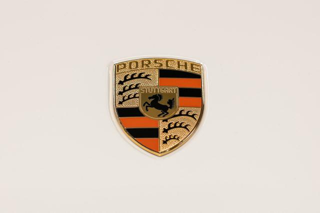 (FILES) The Porsche emblem is pictured on a Porsche 911 S/T at the "Exclusive Manufaktur" of German luxury car maker Porsche, where clients can get their vehicles customized in Stuttgart - Zuffenhausen on March 6, 2025. Porsche reiterated at a press conference on March 11, 2026 a desire to “extend the lifespan of its combustion and hybrid engines,” in the face of a slower-than-expected adoption of electric vehicles in Europe and the United States. (Photo by SILAS STEIN / AFP)