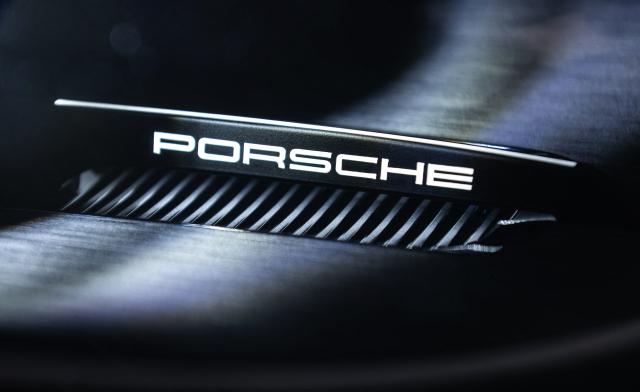 (FILES) The Porsche lettering is pictured on a Porsche 911 headlight at the "Exclusive Manufaktur" of German luxury car maker Porsche, where clients can get their vehicles customized in Stuttgart - Zuffenhausen on March 6, 2025. Porsche reiterated at a press conference on March 11, 2026 a desire to “extend the lifespan of its combustion and hybrid engines,” in the face of a slower-than-expected adoption of electric vehicles in Europe and the United States. (Photo by SILAS STEIN / AFP)
