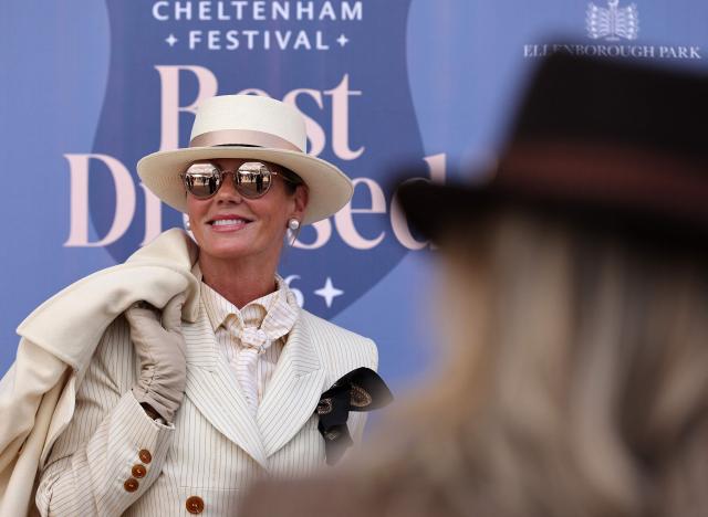 A racegoer poses for photographs as they arrive on the second day of the Cheltenham Festival at Cheltenham Racecourse, in Cheltenham, western England on March 11, 2026. (Photo by Adrian Dennis / AFP)