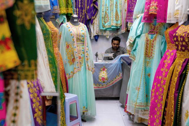 TOPSHOT - A tailor operates a sewing machine at a dress shop in a bazaar in Bahrain's capital Manama on March 11, 2026. Iran's Revolutionary Guards said on March 11 that they had targeted several US bases in Kuwait and Bahrain during the war with the United States and Israel. (Photo by AFP) / 