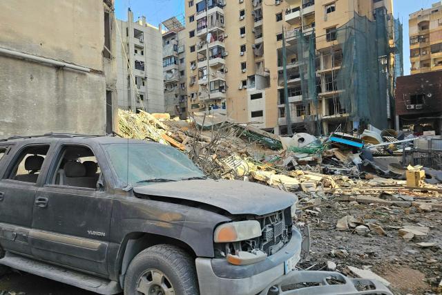 A car is seen amid debris near a damaged building after an Israeli airstrike in Beirut's southern suburb neighborhood of Ruwais on March 11, 2026. Israel pressed its attacks across Lebanon on March 11, hitting an apartment building in central Beirut, in the second targeting of the heart of the capital since the Middle East war began. (Photo by AFP) / 