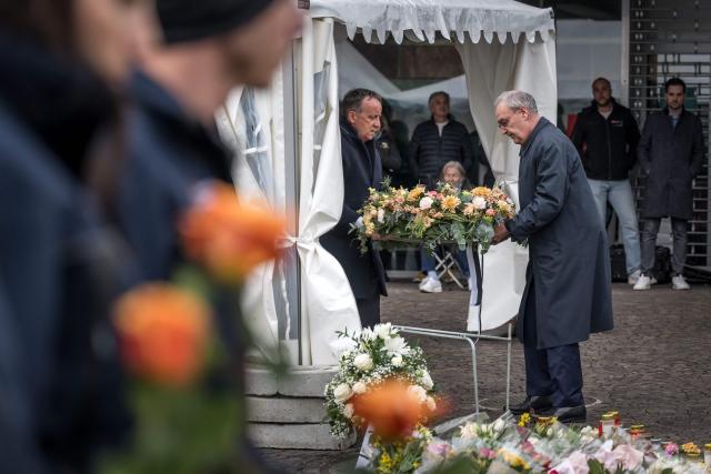 Switzerland's President Guy Parmelin (R) and President of the government of the Canton of Fribourg Philippe Demierre (L) lay a bouquet of flowers to pay their respect during a memorial ceremony in Kerzers, western Switzerland on March 11, 2026, the day after six people were killed in a bus fire which was seemingly started by a disturbed man on board who set himself alight. (Photo by Fabrice COFFRINI / AFP)