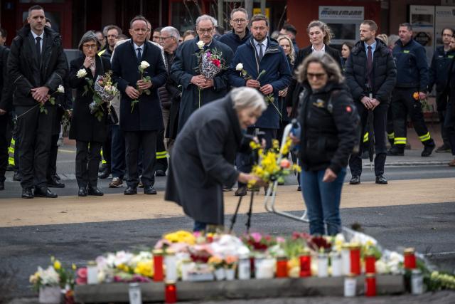 Switzerland's President Guy Parmelin (4th L) and President of the government of the Canton of Fribourg Philippe Demierre (3rd L) hold flowers during a memorial ceremony in Kerzers, western Switzerland on March 11, 2026, the day after six people were killed in a bus fire which was seemingly started by a disturbed man on board who set himself alight. (Photo by Fabrice COFFRINI / AFP)