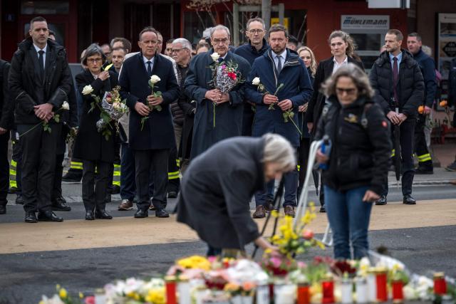 Switzerland's President Guy Parmelin (4th L) and President of the government of the Canton of Fribourg Philippe Demierre (3rd L) hold flowers during a memorial ceremony in Kerzers, western Switzerland on March 11, 2026, the day after six people were killed in a bus fire which was seemingly started by a disturbed man on board who set himself alight. (Photo by Fabrice COFFRINI / AFP)
