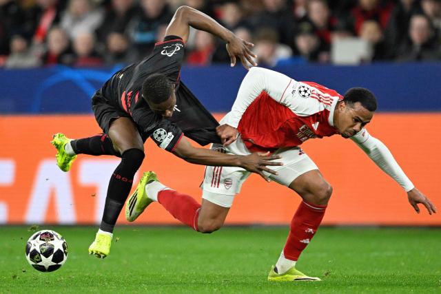 Arsenal's Brazilian defender #06 Gabriel Magalhaes (R) and Bayer Leverkusen's Cameroonian forward #35 Christian Kofane vie for the ball during the UEFA Champions League, Last 16, first-leg football match Bayer 04 Leverkusen vs Arsenal in Leverkusen, western Germany, on March 11, 2026. (Photo by INA FASSBENDER / AFP)