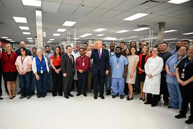 US President Donald Trump speaks with employees as he tours Thermo Fisher Scientific laboratories in Cincinnati, Ohio, on March 11, 2026. Trump is meeting with Thermo Fisher officials to discuss prescription drug prices. (Photo by Jim WATSON / AFP)